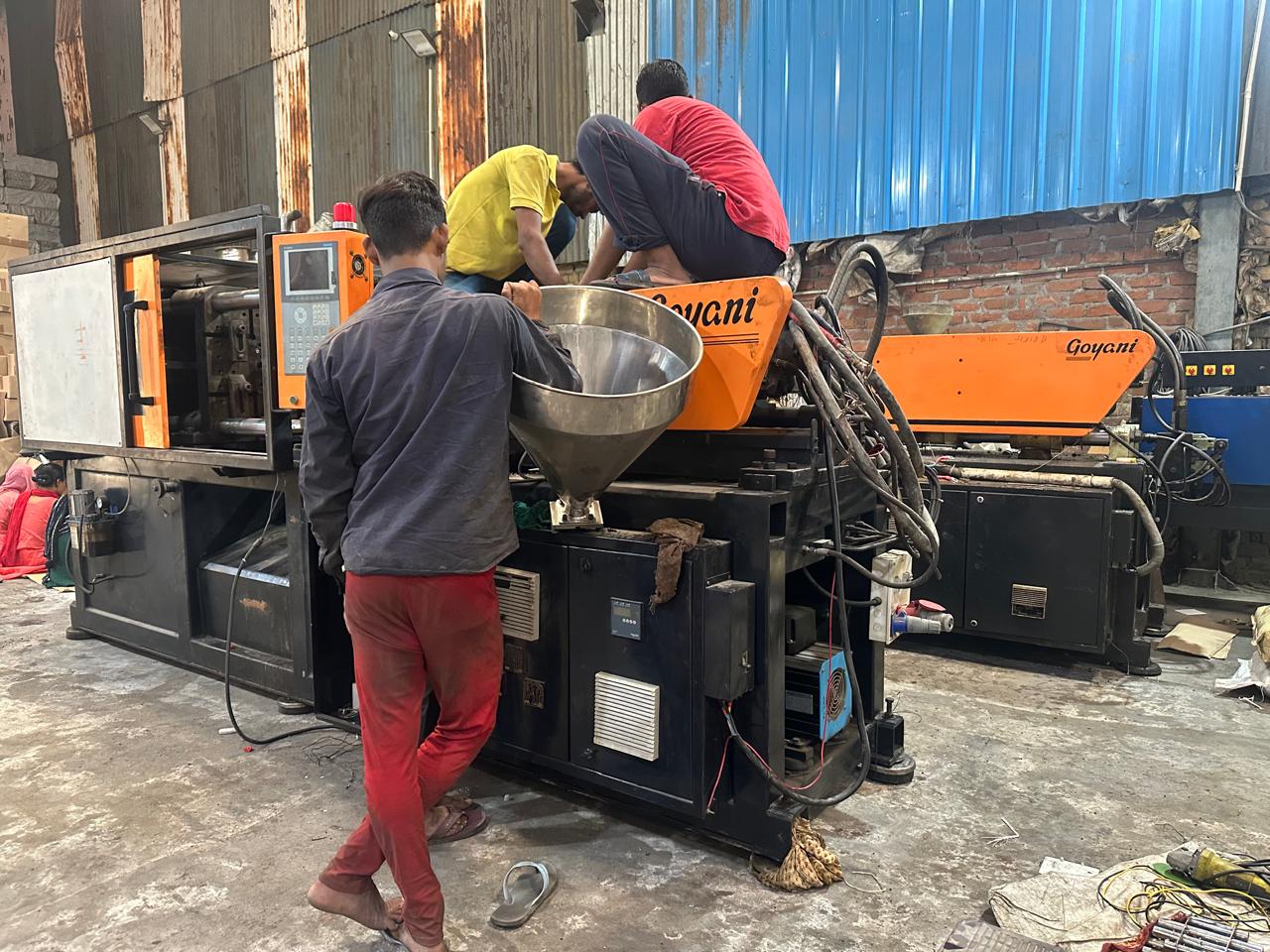 Workers operating an injection moulding press on the shop floor